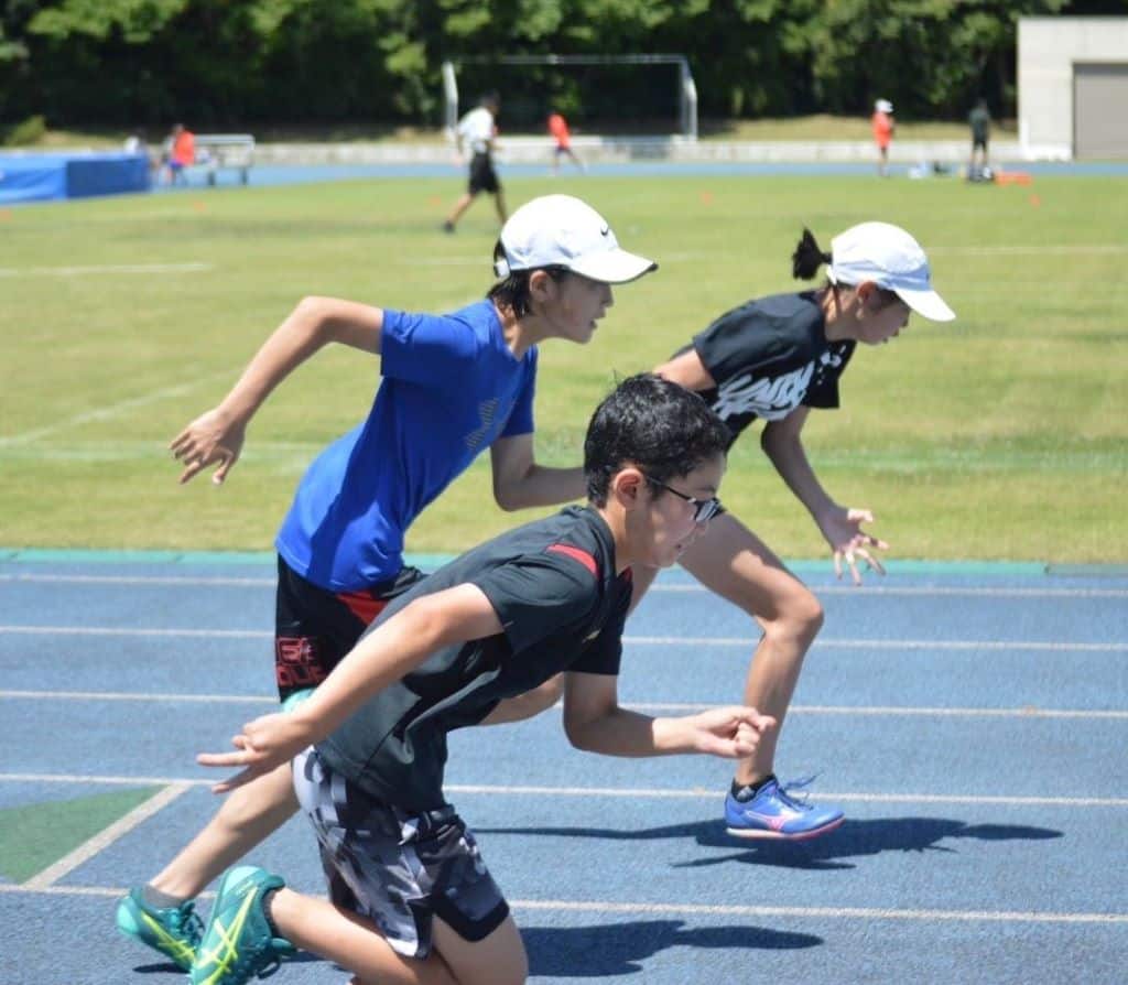 陸上競技場で走るクラブチーム生徒の写真
